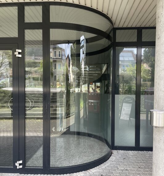 eine gebogene Glasscheibe in einem Hauseingang